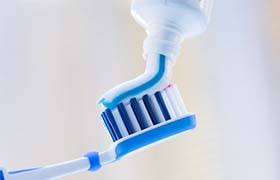 toothpaste being put onto a blue toothbrush