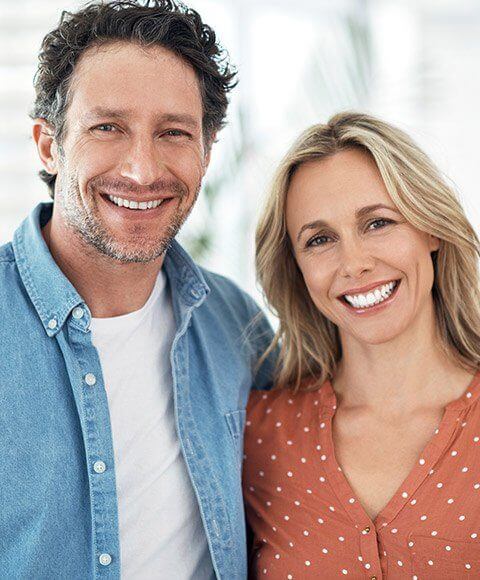 Man and woman smiling while standing next to each other