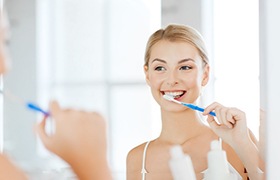 Woman looking in mirror and brushing her teeth
