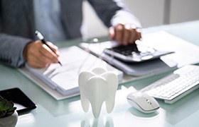 A large model tooth in front of a person calculating a bill