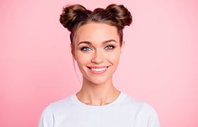 young woman in white shirt smiling against pink background 