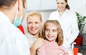 Young girl sitting in dental chair with her mother.