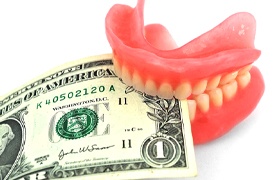 dentures biting money representing the cost of dentures in Aurora