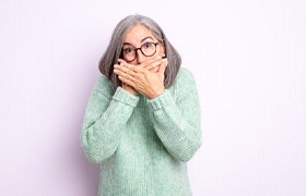a woman covering her mouth due to tooth loss