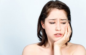Woman with a toothache needing an emergency dentist in Aurora.