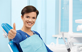 Smiling woman in dental chair giving thumbs up