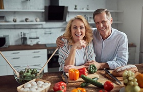 Couple preparing meal while enjoying benefits of dental implants in Aurora