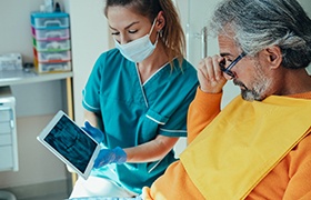 Dentist explaining why patient’s dental implants in Aurora are failing