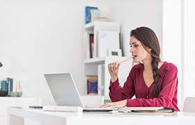 woman sitting at a desk and chewing on a pencil