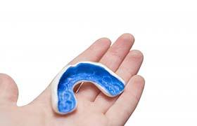 person holding a blue mouthguard in their hand