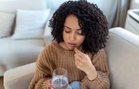 Woman following dental implant post-op instructions by taking medication