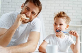 Father and son brushing their teeth together