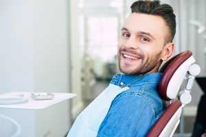 Male dental patient sitting in chair and smiling