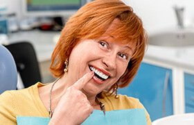 Smiling woman pointing to tooth