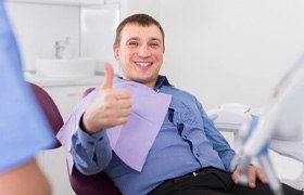 : Smiling man in dental chair giving a thumbs-up for sedation dentistry  