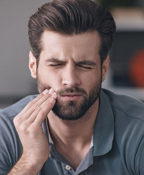 Man in pain holding the side of his cheek