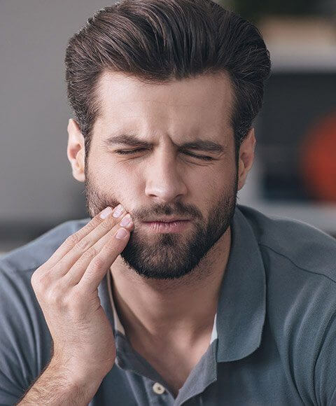 Man in pain holding cheek