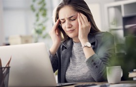 Woman touching her temples at work 