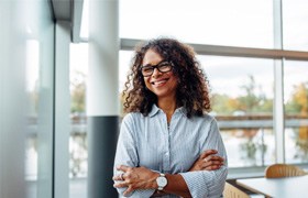 Businesswoman in button-up shirt smiling with arms folded