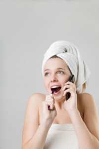 Woman chatting on phone and brushing teeth in a towel needs to visit the dentist aurora trusts