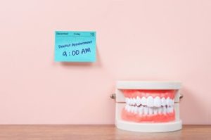 A sticky note on a wall reading “dental appointment, 9 am” next to a dental diagram