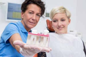 Dentist holding model of dental implants in Aurora. 