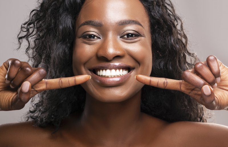 young woman pointing to perfect white smile