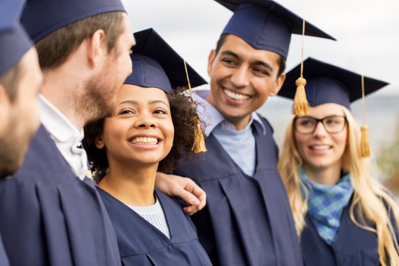 Graduating students smiling and talking to one another