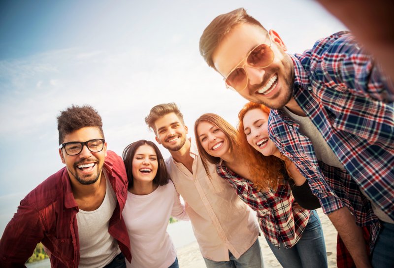 Cosmetic dentistry patient smiling with friends on beach