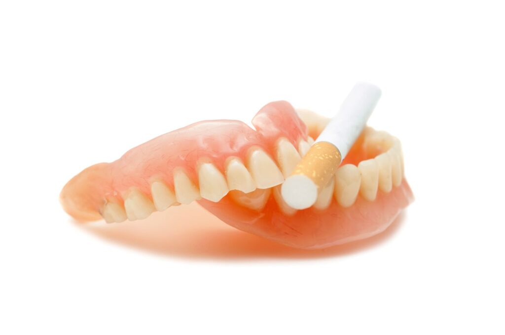 Fresh cigarette resting on a complete set of dentures